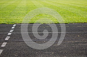 An empty football field. Soccer field grass. Graphite running road track with white marking lines near green football