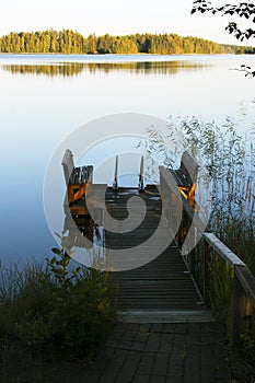 Empty footbridge with a bench on a lake at sunrise