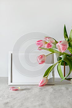 Empty frame and bouquet of tulips on neutral beige background. Aestethic spring mock up or template, copy space