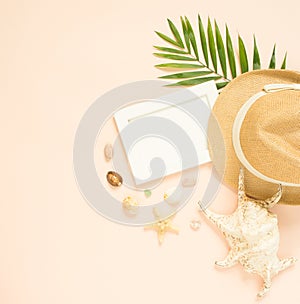 Empty frame and summer holidays items on creme background. Straw hat, seashells and starfish. Selective focus. Place for text. Fla
