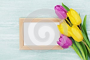 Empty frame and tulip flowers on rustic table for March 8, International Womens day, Birthday or Mothers day