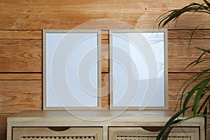 Empty frames on table near wooden wall. Mockup for design