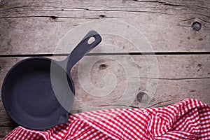 Empty frying pan on aged wooden background.