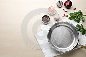 Empty frying pan, fresh vegetables, spices and basil on table, flat lay. Space for text