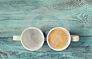 Empty and full cup of fresh coffee on vintage blue table