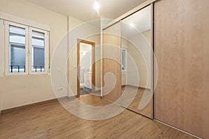 Empty furniture room with built-in wardrobe with large mirror door