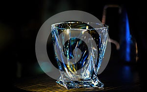 An empty glass beaker glows on a dark background.