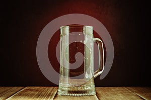 empty a glass from beer on a red light background/empty a glass from beer on a wooden table and a red background, selective focus