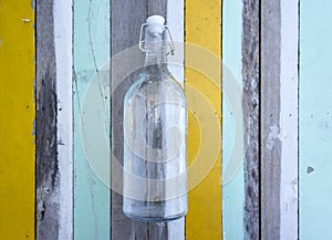 Empty glass bottle against multi colored wooden