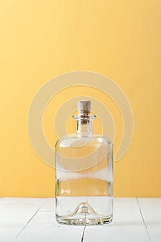 Empty glass bottle for rum on a light white-yellow background