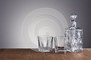 Empty glass carafe, prepared for the alcohol drink on grey background and wood