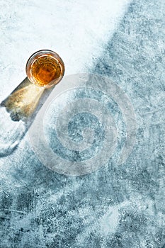 Empty glass with drink casting shadows on textured rustic concrete background