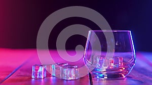 In empty glass, falling ice cubes. bounce each other. Color lighting. closeup.