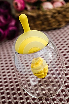 Empty Glass Honey Jar with Yellow Cap on Fabric Tablecloth