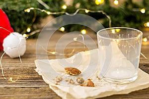 empty glass from milk and crumbs from cookies for Santa Claus in front of a Christmas tree lights bokeh