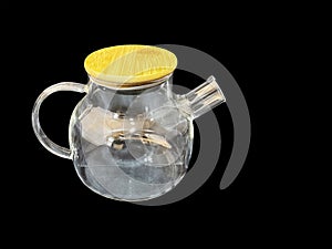 Empty glass teapot with wooden lid on black background