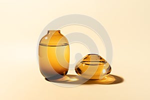 Empty glass vases with water on beige background with hard long shadows