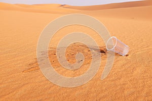 Empty glass of water on a desert land showing dehydration and water shortage concept