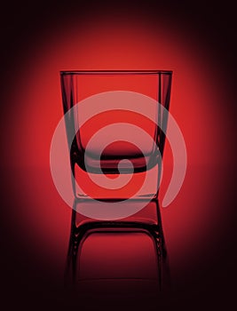 Empty glass for water, whiskey, juice or other drink on a rich dark red gradient background