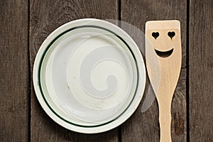 Empty glass white crockery and wooden spatula with a smile on a wooden table, kitchen utensils