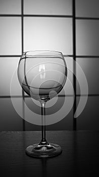 Empty glass for wine and champain isolated on table against squared background black and white monochrome.