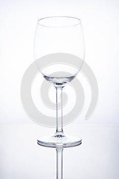 Empty glass wine goblet on white background with reflection