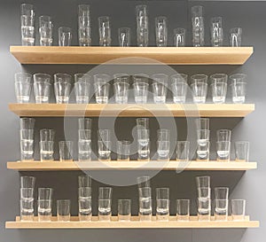 Empty glass on wooden shelf and gray wall