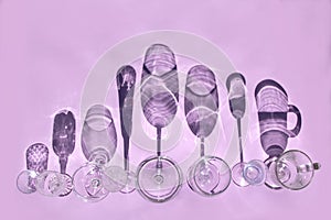 Empty glasses of different forms for wine, whiskey, mulled wine, vodka, liquor stand in row on pink background in sunlight with