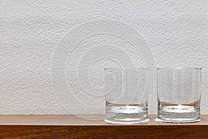 Empty glasses are placed on a wooden shelf in the kitchen