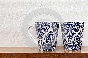 Empty glasses are placed on a wooden shelf in the kitchen