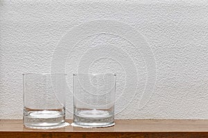 Empty glasses are placed on a wooden shelf in the kitchen