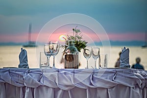 Empty glasses are on the served table. Against the backdrop of a sunset in the sea on a sandy beach