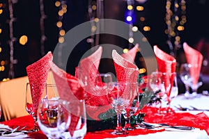 Holiday red decorations in restaurant. Empty glasses set with red holiday decoration and bokeh background.