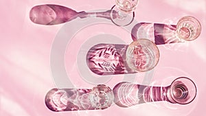 Empty glasses of various shapes for wine, whiskey, mulled wine, vodka, liqueur stand on a pink background in the sunlight with sha