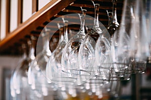 Empty glasses for wine above a bar rack. Hanging wine glasses in