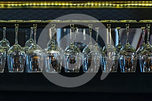 Empty glasses for wine and beverage above a bar rack in restuarant photo
