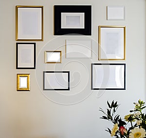 Empty gold and black photo and picture frames on white wall, mock up for your photos or text, copy space modern design luxury