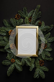 Empty golden border with garland of fir branches on a black background