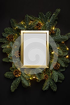 Empty golden border with garland of fir branches and lights on a black background