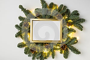 Empty golden border with garland of fir branches and lights on a white background