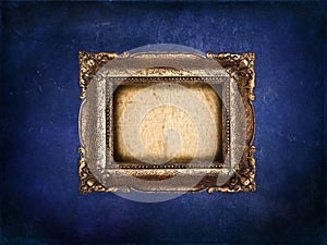 Empty golden frame on blue grunge wall