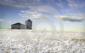 Empty grain silo and shed on a harvested field.