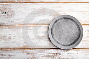 Empty gray ceramic plate on white wooden background. Top view, copy space