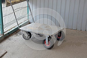 Empty gray metal cargo cart with black wheels
