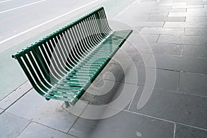 Empty Green iron bench on a roadside, footpath.