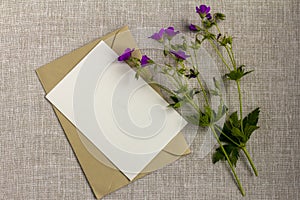 An empty greeting or invitation card, an invitation layout with meadow purple flowers on a gray tablecloth.Rustic style.