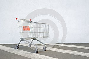 Empty Grocery Cart on the White Wall Store. Trolley at the Supermarket Background. E-commerce. Shopping Concept. Side