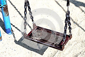 Empty grunge chain swing hanging in playground