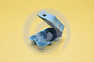 Empty half dozen egg carton container on yellow in center