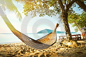 Empty hammock between palm trees on tropical beach. Paradise Island for holidays and relaxation.